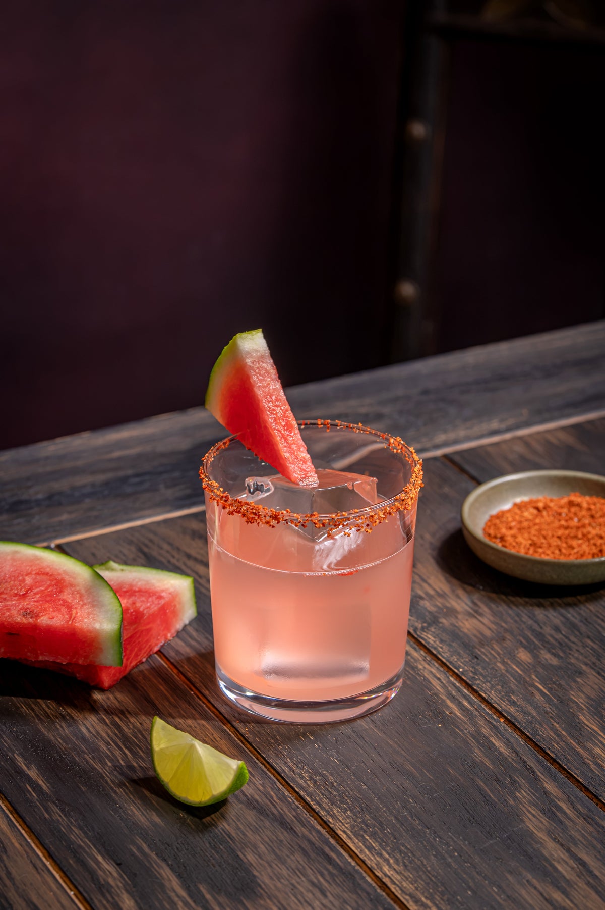 Pink watermelon and chilli Margarita served over ice in a clear tumbler with a chilli-salt rim and watermelon garnish.